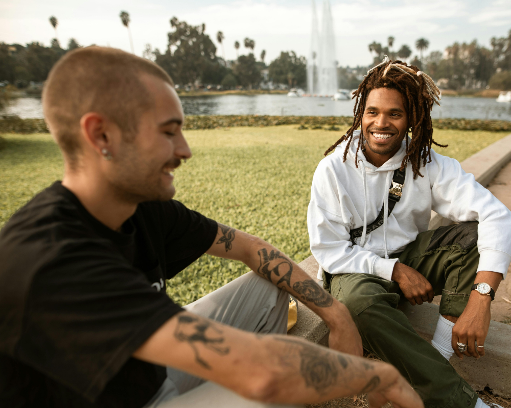 zwei junge Menschen sitzen im Park und lachen miteinander