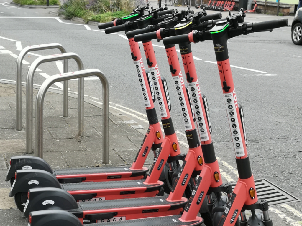 mehrere rote E-Roller stehen nebeneinander bei einem Fahrrad Absperrplatz