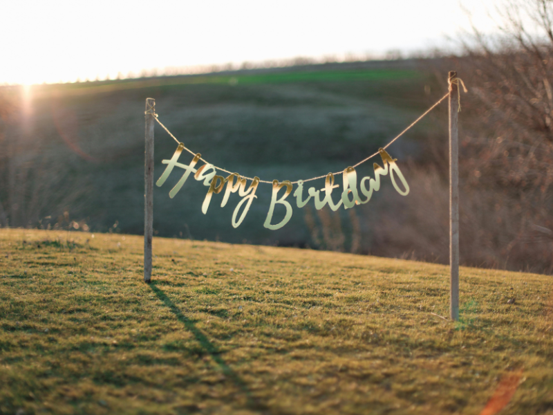 Auf einem Feld steht eine Girlande auf der "Happy Birthday" steht