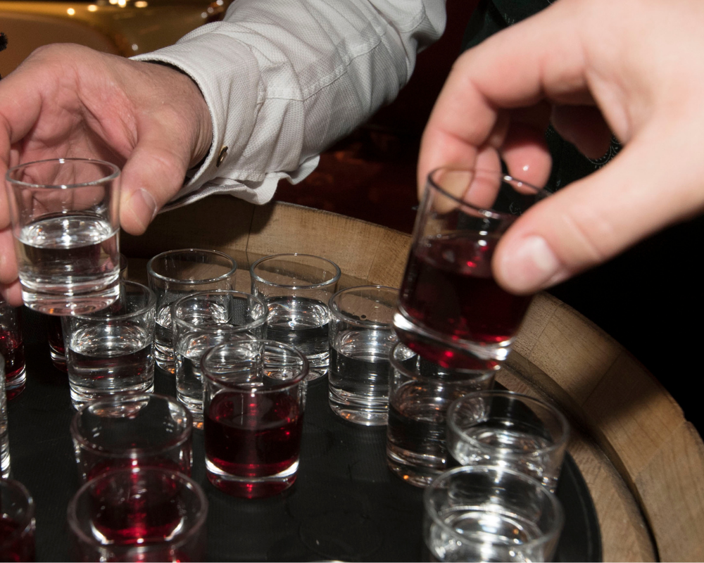 Mehrere Shotgläser nach denen Personen greifen 