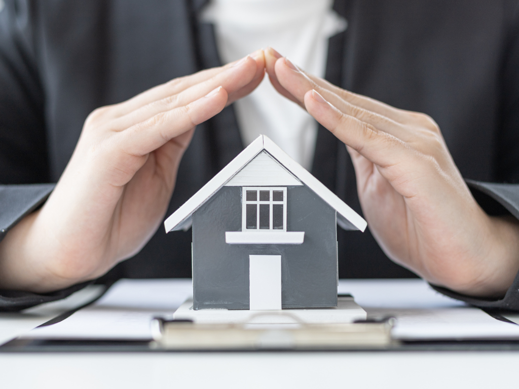 Hände über einem Haus gefaltet 