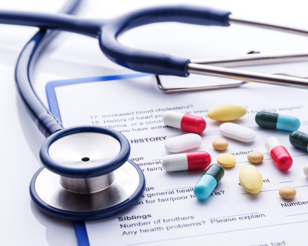 ein Stethoskop, ein Dokument und Medikamente liegen auf einem weißen Hintergrund