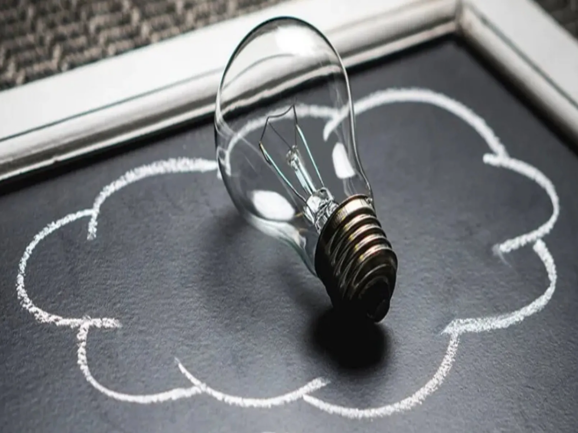 Eine Glühbirne liegt in einer mit Kreide gezeichneten Wolke