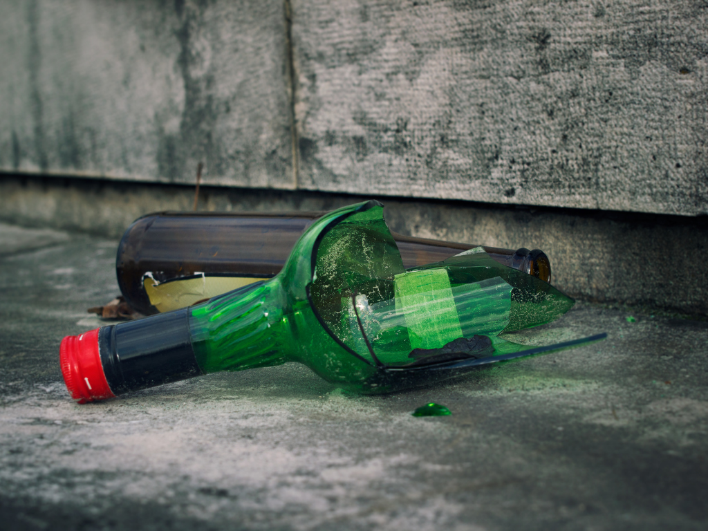 eine zerbrochene Weinflasche liegt auf der Straße