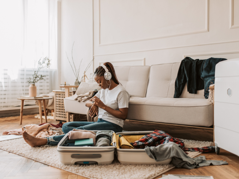 Eine Person sitzt am Boden und packt ihren Koffer 