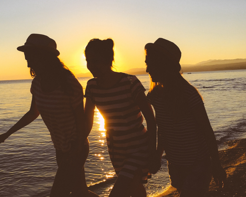 Drei Freundinnen sind bei Sonnenuntergang am Strand