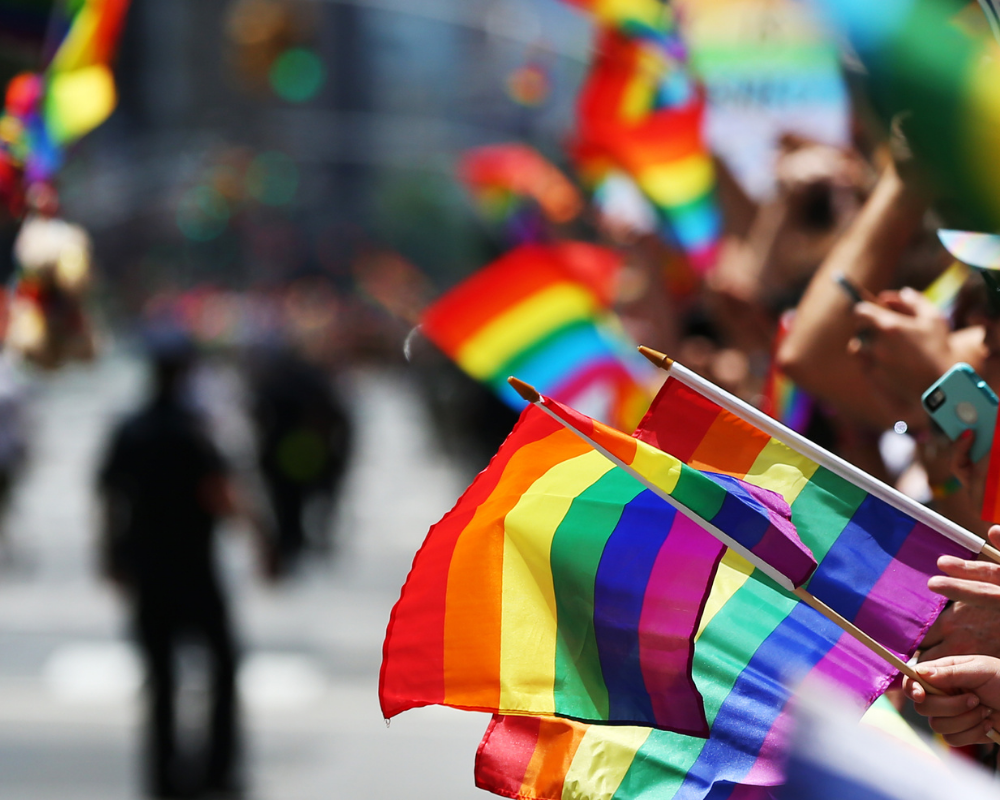 mehrere Regenbogenfahnen werden in die Luft gehalten