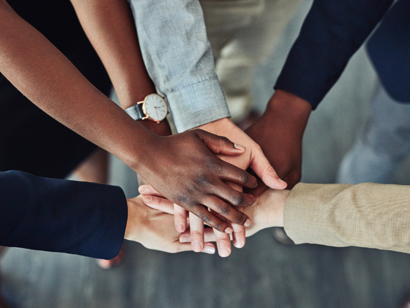 mehrere Personen geben ihre Hände stärkend zusammen 