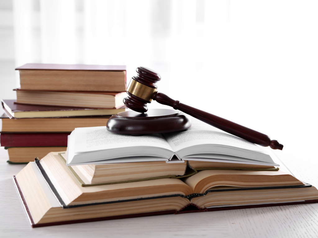 Gesetzesbücher auf einem Tisch mit einem Richterhammer darauf