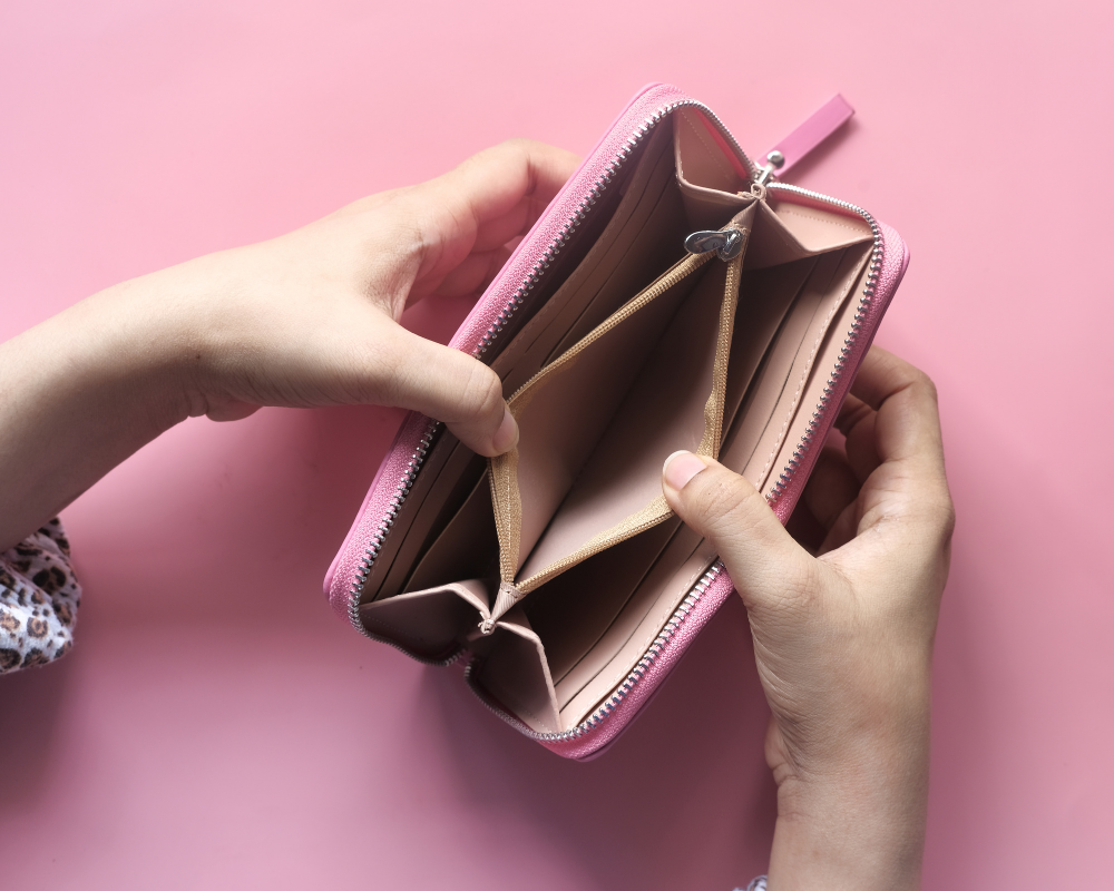 Leere Geldbörse vor einem rosa Hintergrund