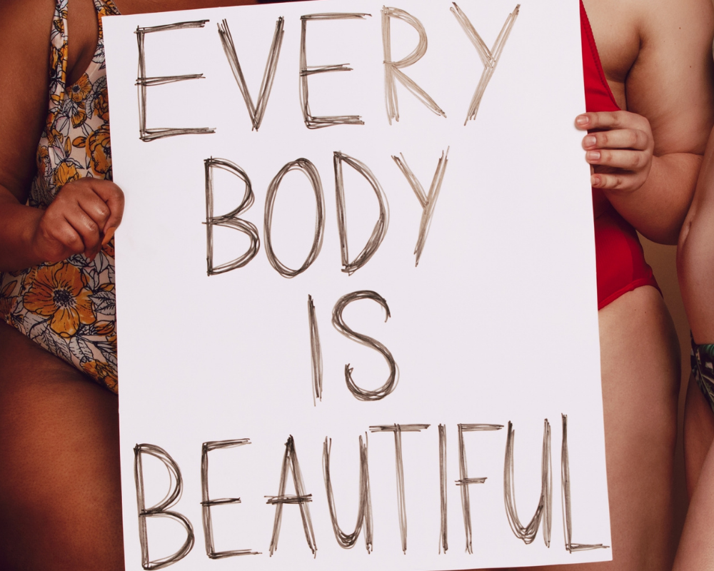 Personen halten ein Schild auf dem steht "Everybody is beautiful"