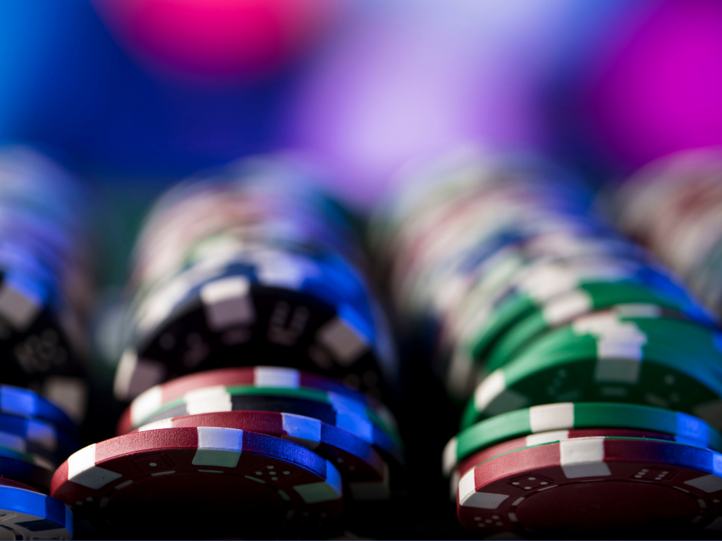 Poker Spielchips aufgereiht vor einem pinken Hintergrund