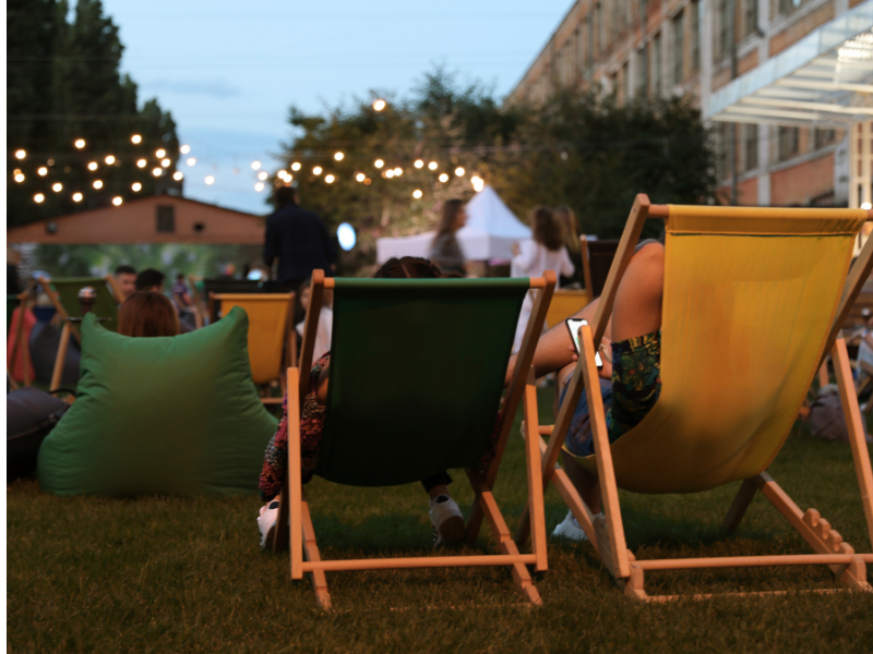 Zwei hölzerne Liegestühle und ein großer, grüner Sitzsack stehen auf einer Rasenfläche.