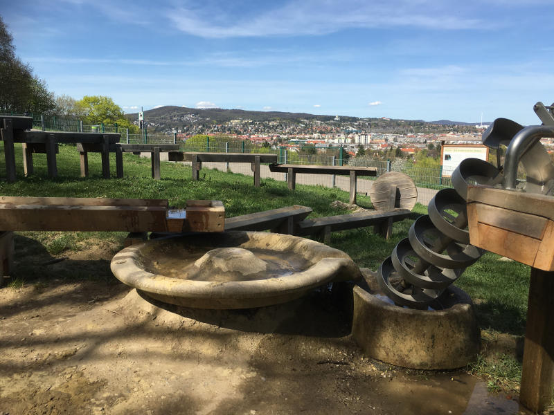 Holzwasserbahn sowie Metall-Wasserspirale. Im Hintergrund ist Wien zu sehen.