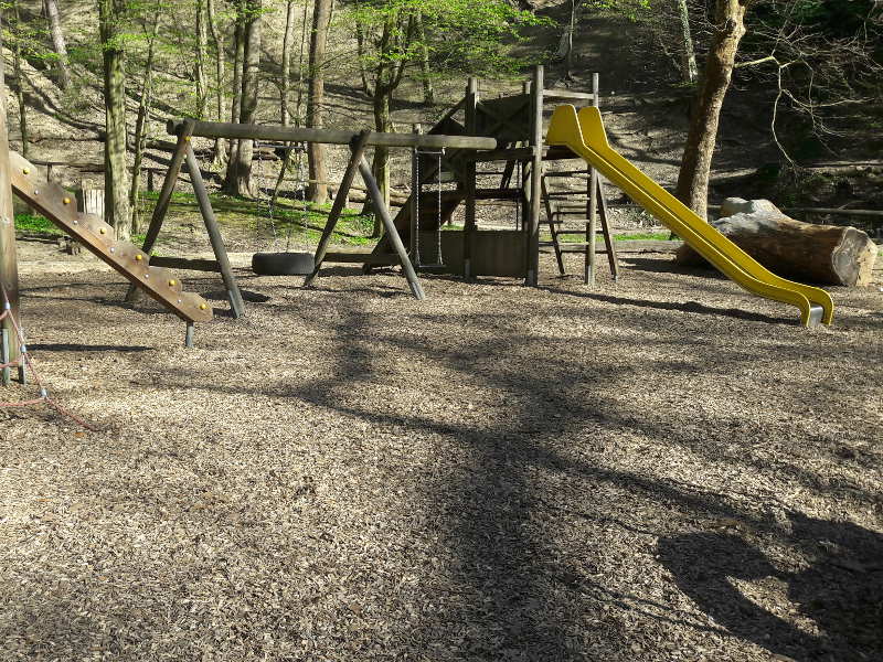 Spielplatz im Wald mit Rutsche und Schaukel