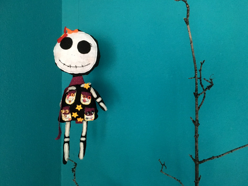 Bunte gebastelte Catrina, die an einem Faden in einem türkisen raum hängt
