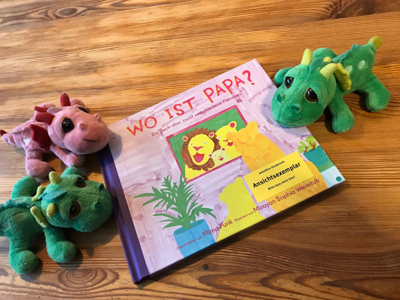 WoIstPapa Drei Plüschdrachen um ein Buchcover: Wo ist Papa? Ein Buch über zwölf verschiedene Familien von Mirna Funk und Maayan Sophia Weisstub.
