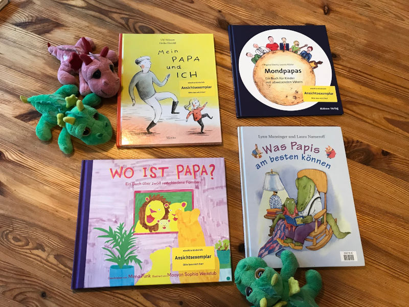 Drei Plüschdrachen und Büchercover von Mein Papa und ich von Ulf Nilsson und Heike Herold, Mondpapas von Regina Deertz und Leonie Rösler, Wo ist Papa? von Mirna Funk und Maayan Sophia Weisstub sowie Was Papis am besten können von Lynn Munsinger und Laura Numeroff.