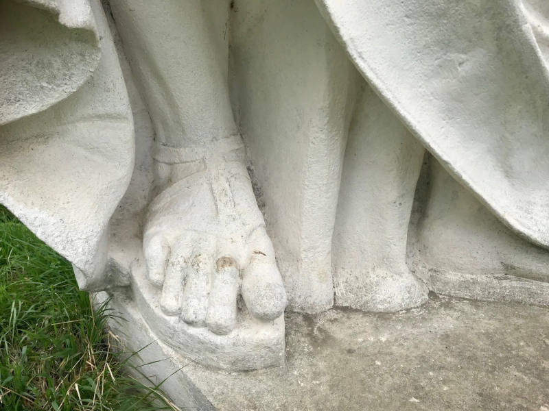 Fuß einer Statue in Sandale von oben fotografiert.