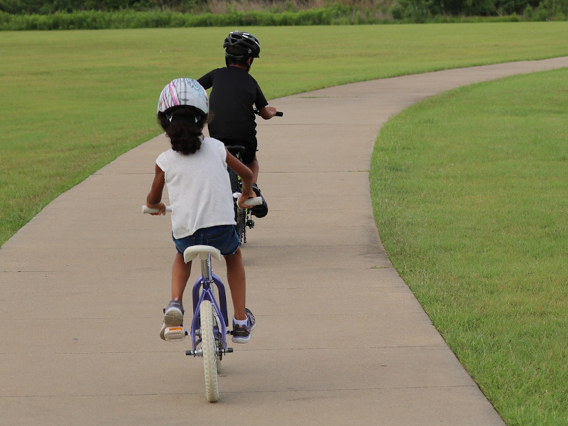 Zwei Kinder auf Fahrrädern fahrend von hinten.