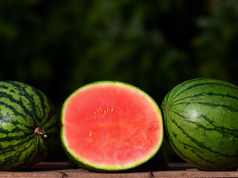 eine Halbe Wassermelone in der Mitte, daneben ganze