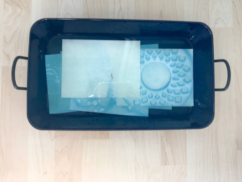 Blaues Reindl, in welchem blaue Papierplätter liegen