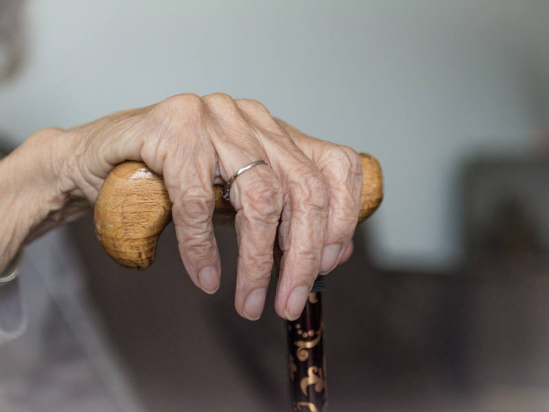 Nahaufnahme von älterer Hand auf einem Gehstock.