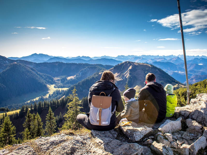 Menschen auf einem Berg 3 Menschen von hinten, die auf einem Berg sizten mit herrlicher Aussicht auf andere Berge