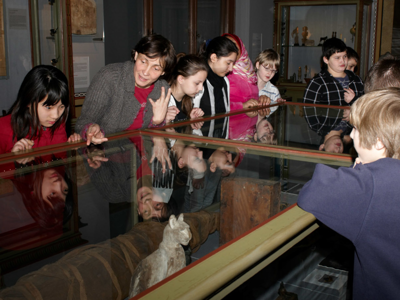 Das Bild zeigt eine Gruppe von Kindern rund um eine Vitrine bei einer Kinderführung im Kunsthistorischen Museum.