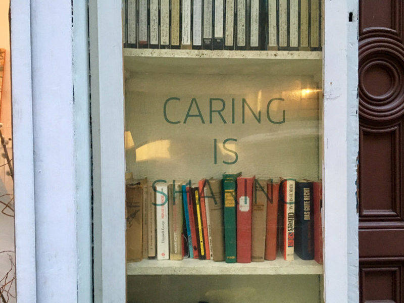 öffentlicher Bücherschrank Bücherschrank mit dem Text Caring is Sharing auf der Glastüre