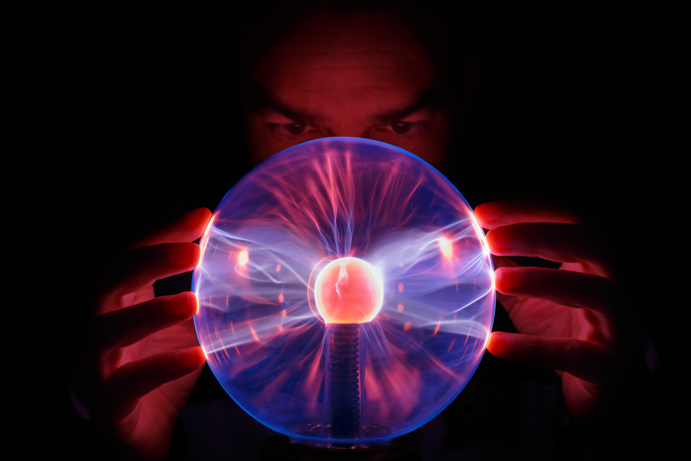 Eine Glaskugel, die Lichtstrahlen enthält. Eine Person hält die Hände an das Glas