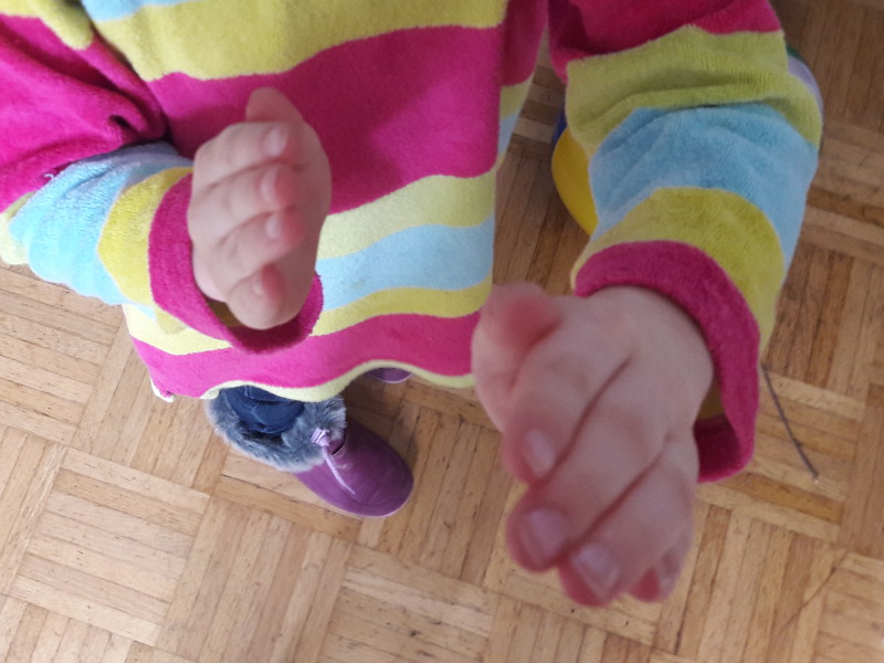 Klatschspiele Kind hebt eine Hand Richtung Kamera.