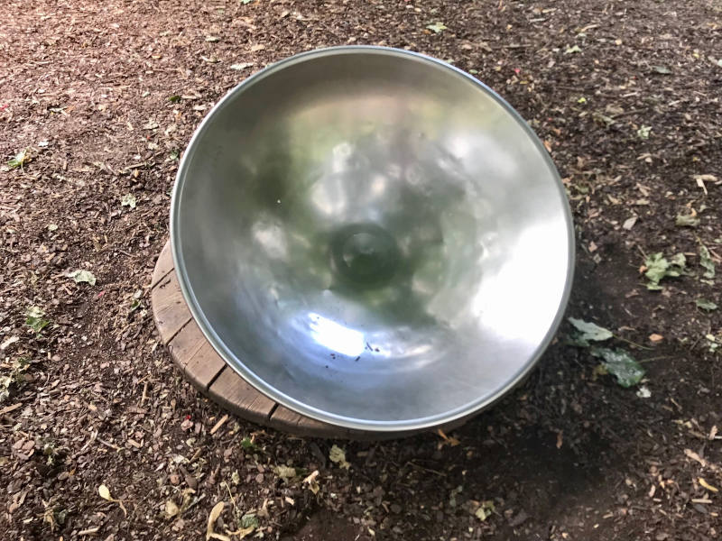 Eine schief montierte Halbkugel aus Metall auf einem drehbaren Holzbrett.