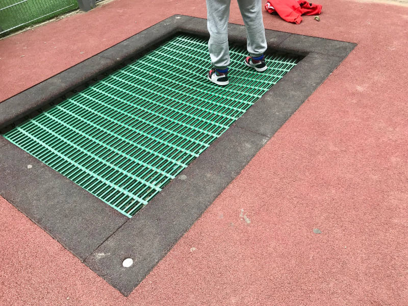 Grünes Bodentampolin, umgeben von rotem EPDM-Boden.