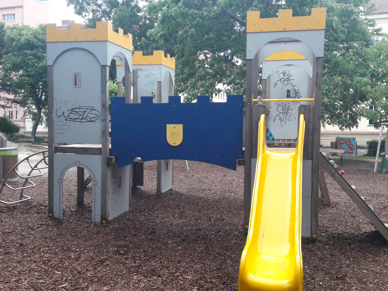 Klettergerüst, das wie eine Burg aussieht mit einer gelben Rutsche.