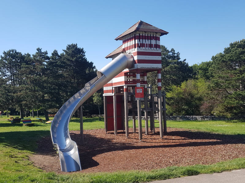 Rot und weißer Turm von dem eine hohe Rutsche runtergeht