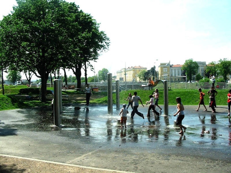 Wasserspiele im Theodor-Körner-Park Kinder laufen durch mehrere Wassersträhle, die aus Bodendüsen kommen