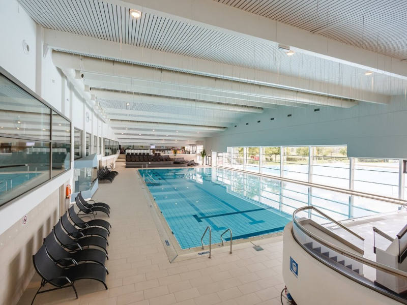 Blick auf ein Schwimmbecken. Auf der linken Seite stehen Liegen.