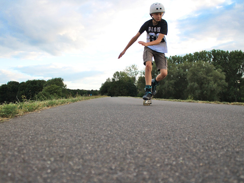 Junge fährt Inline Skates auf einem Gehweg