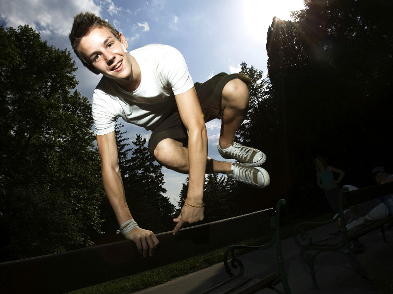 Jugendlicher springt über Parkbank