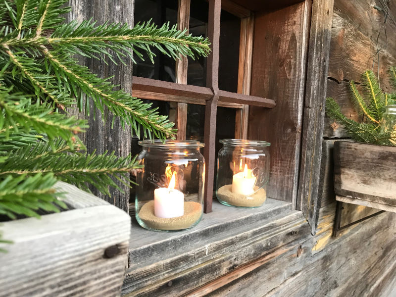 Zwei Kerzen bei einem alten Fenster auf einem Weihnachtsmarkt