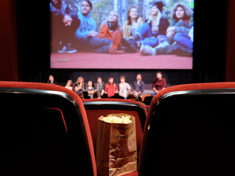 Eine Gruppe an Jugendlichen steht in einem Kinosaal auf der Bühne.