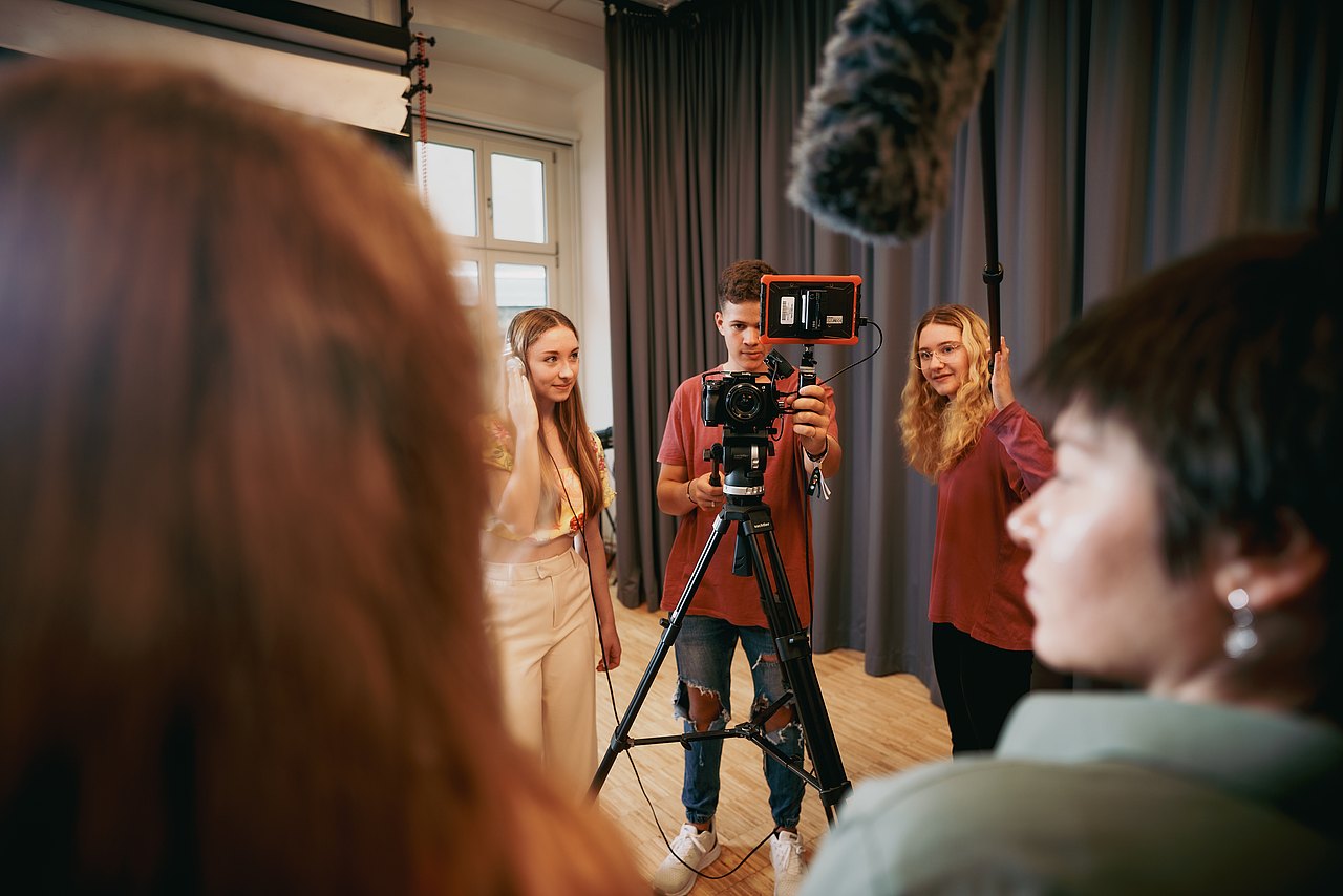 Mehrere Jugendliche filmen eine Szene in einem Studio.