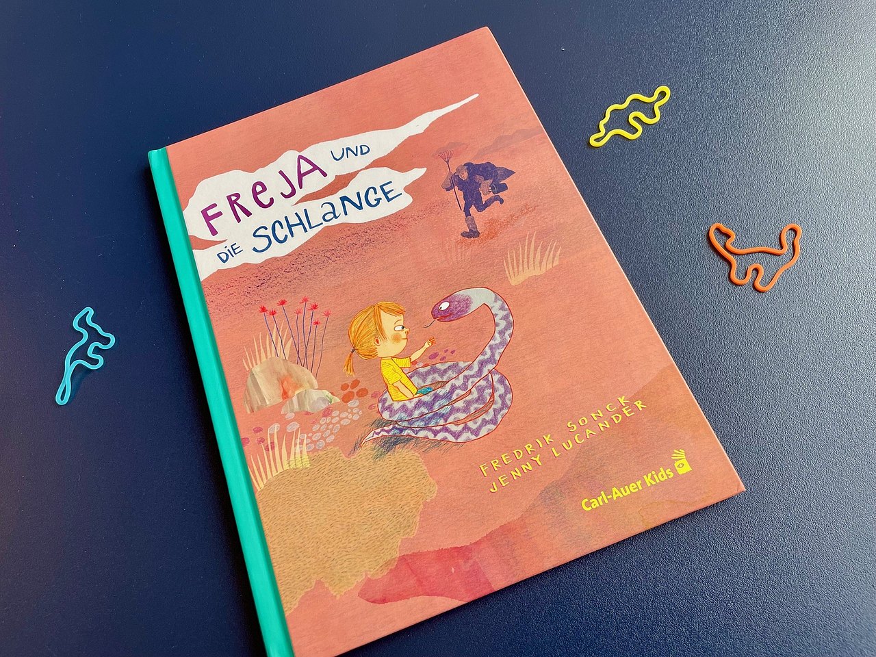 Kinderbuch in warmen Orange-Gelb-Tönen mit Kind und Schlage abgebildet