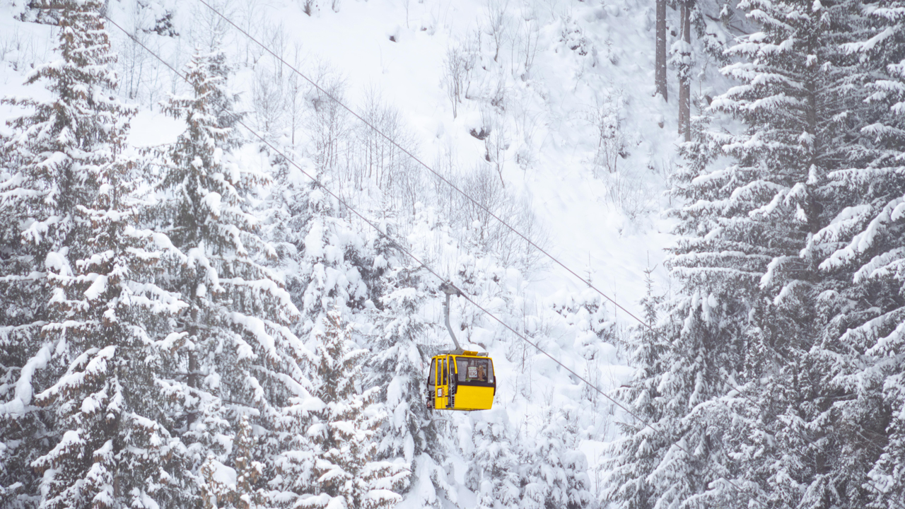 Gelbe Gondel in verschneiter Berglandschaft.