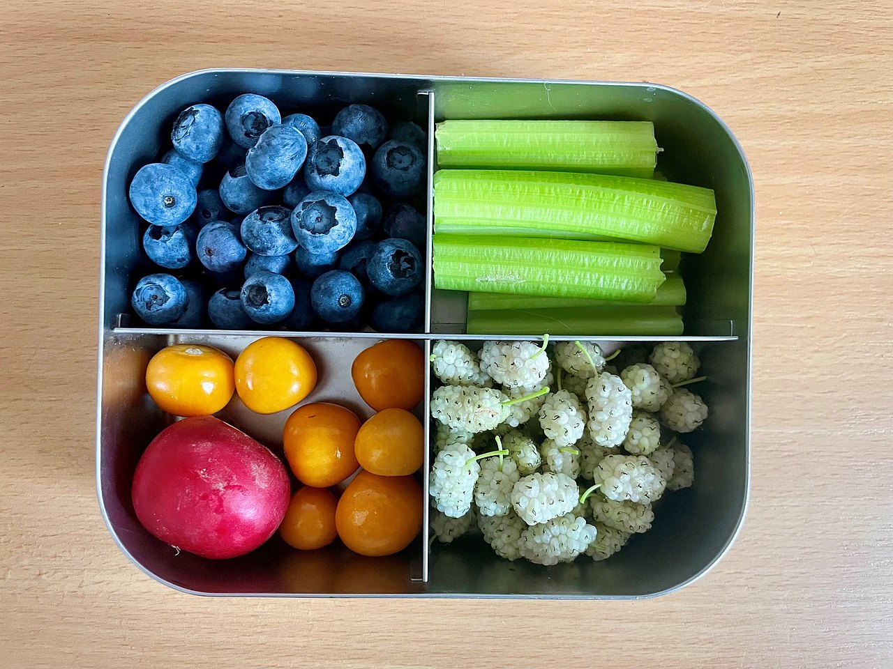 Jausenbox aus Edelstahl mit 4 Unterteilungen in welchen Beeren, Radieschen, Stangensellerie ist