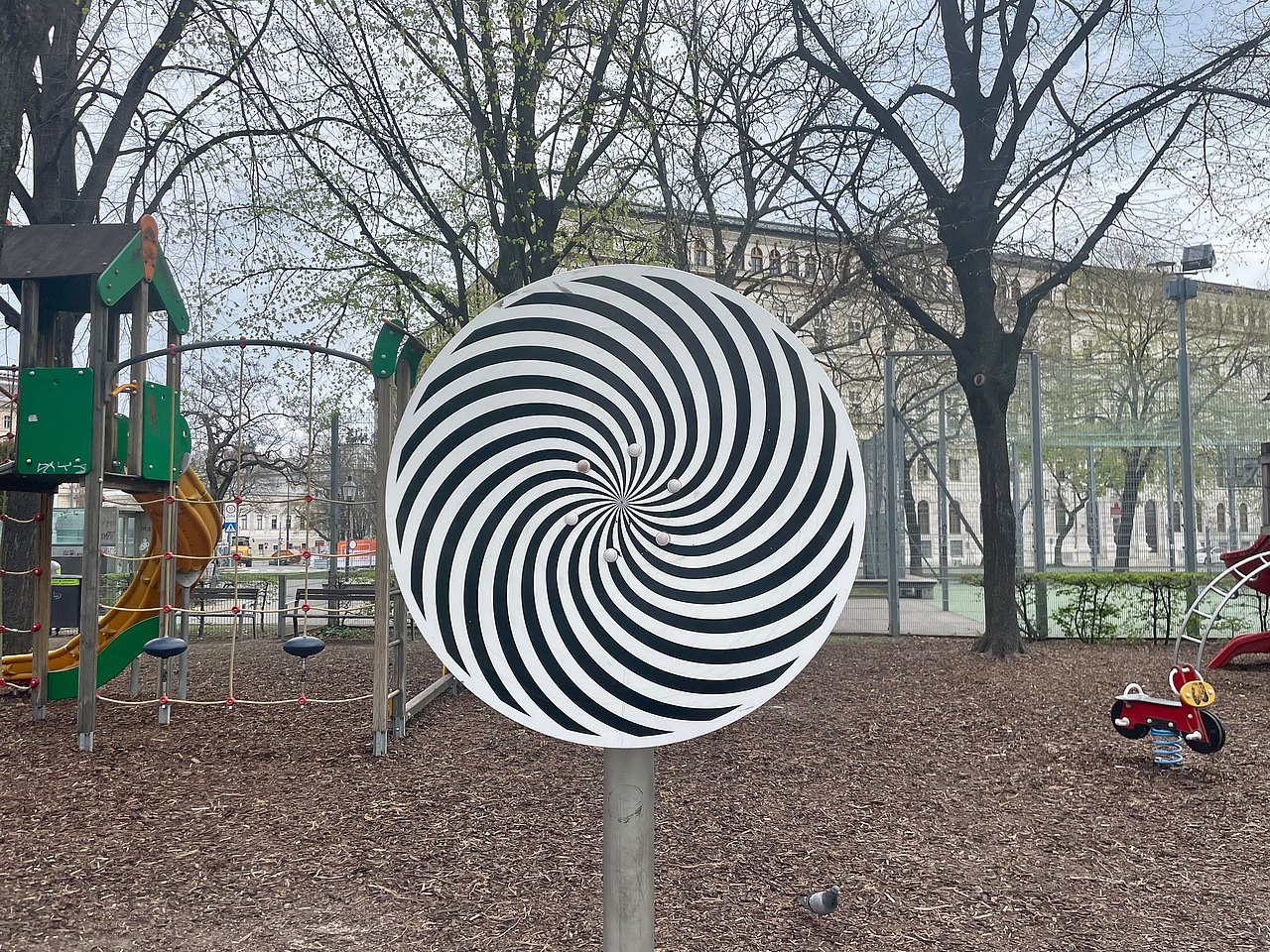 Optisches Spielgerät am Spielplatz Weghuberpark Scheibe in schwarz-weiß, die man drehen kann und die dann ein Muster erzeugt