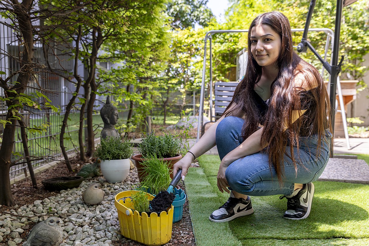 Jugendliche befüllt Blumentöpfe mit Erde