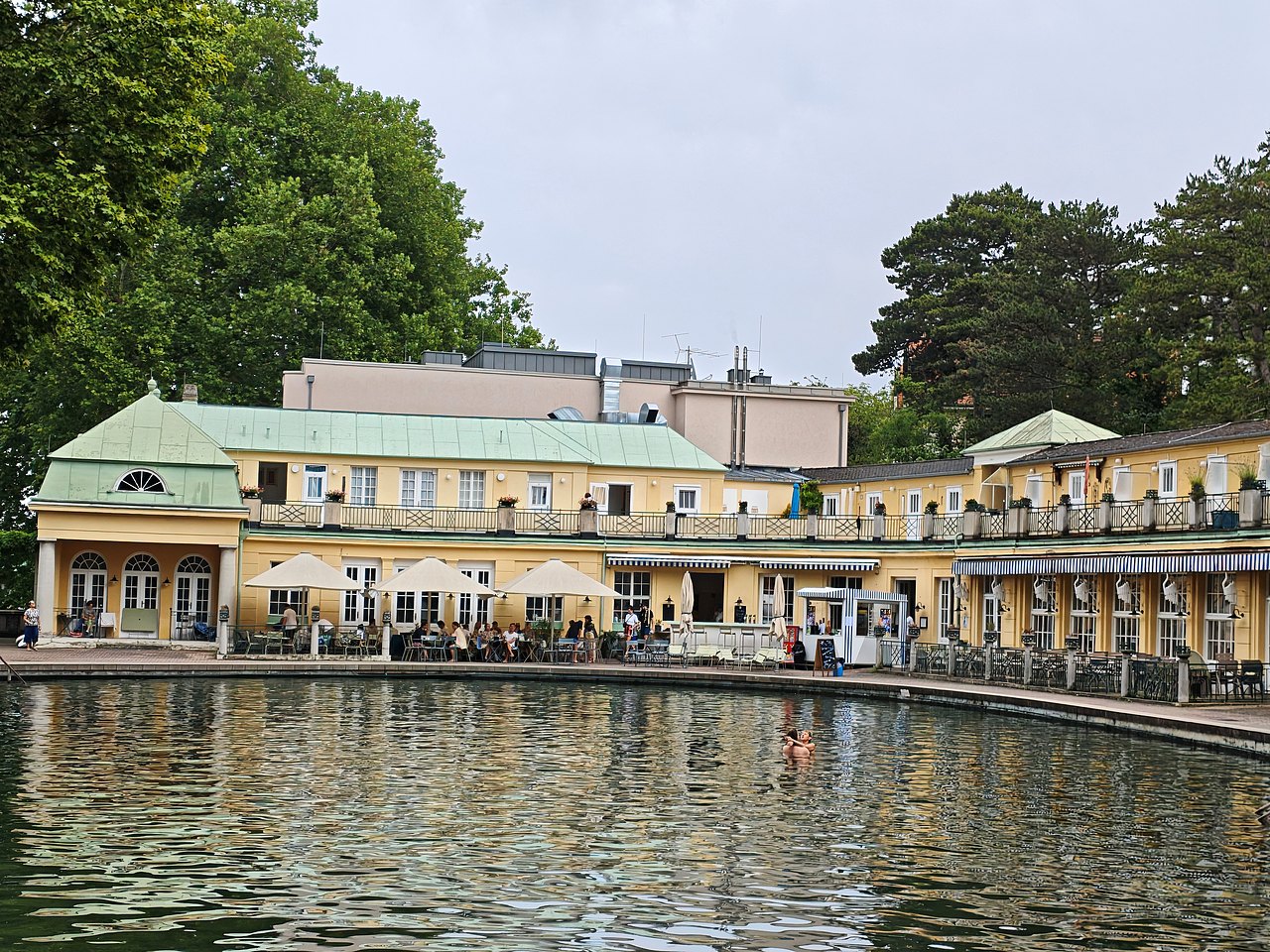 Das Bild zeigt das Grüne Becken von der Insel aus, im Hintergrund ist das Restaurant Kabane 21 mit dem Kiosk, an dem Pommes und Eis angeboten werden.