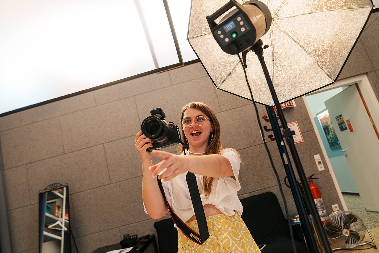 Eine Jugendliche lacht, während sie in einem Studio fotografiert. 